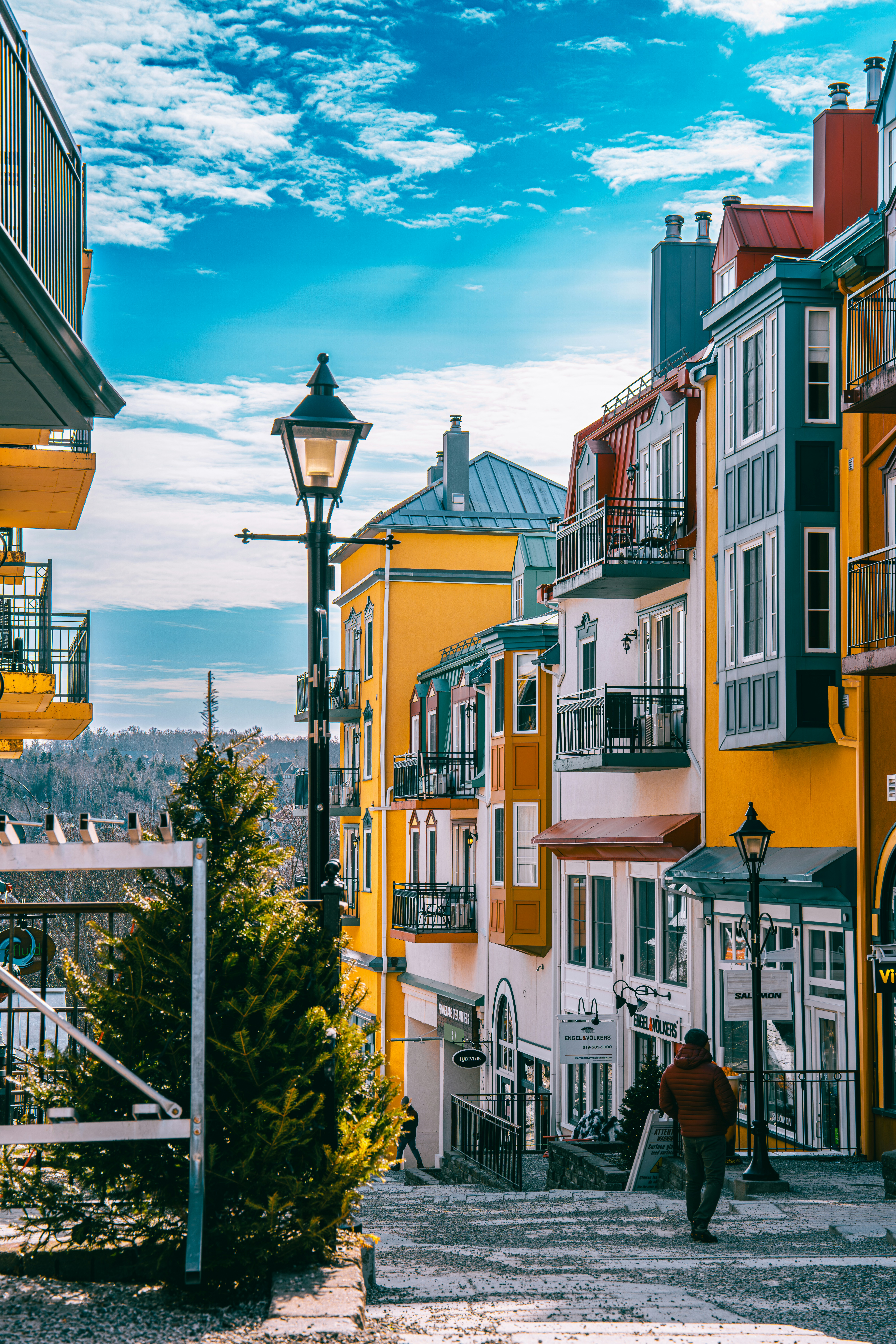 A Man Walking Down A Street Next To Tall Buildings