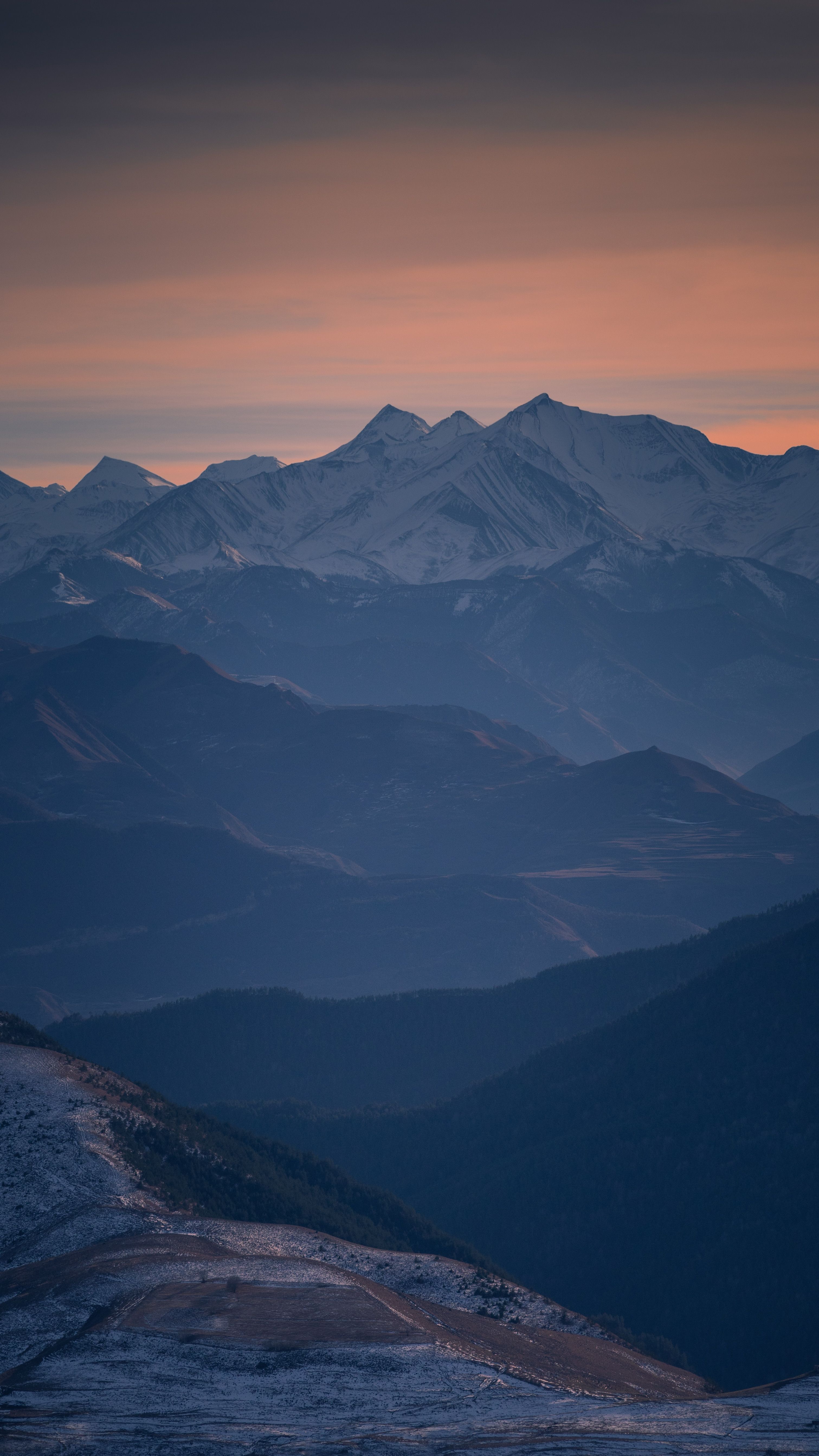 A Stunning View Of Snow-capped Mountains Under A Twilight Sky, Offering A Serene Landscape Scene. HD mobile wallpaper