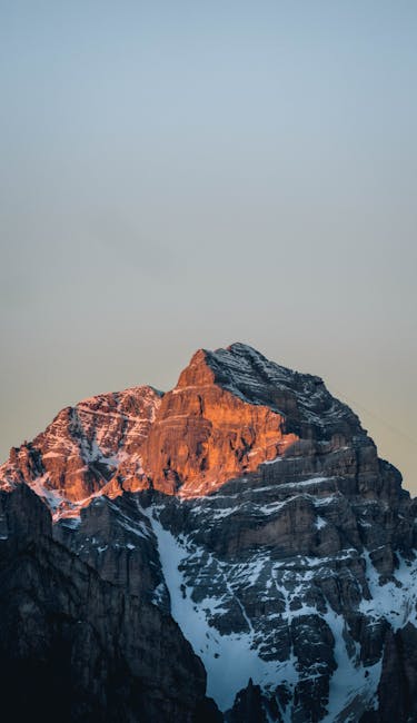 Breathtaking View Of A Sunlit Rocky Mountain Peak Against A Clear Sky. wallpaper preview