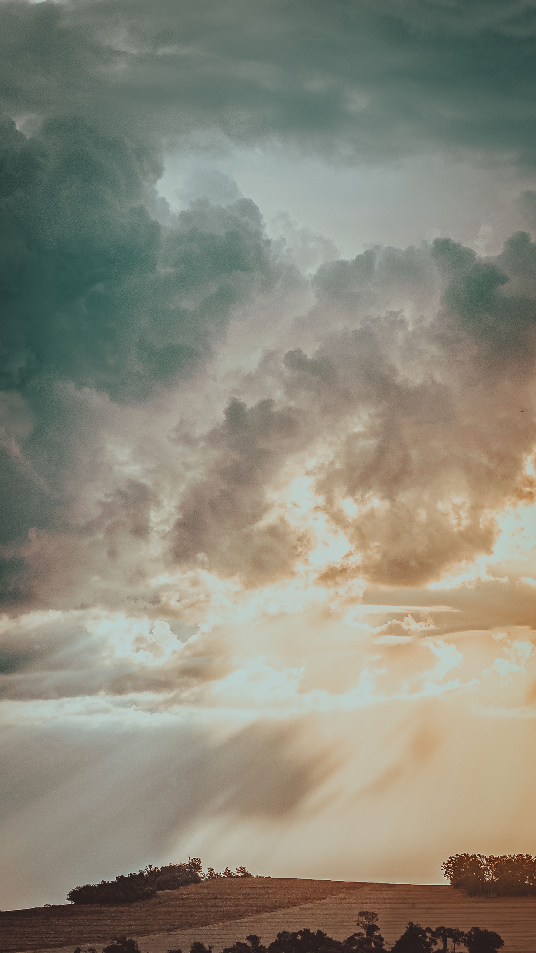 Captivating View Of Dramatic Clouds With Sunbeams Illuminating A Rural Hilltop Landscape. HD mobile wallpaper