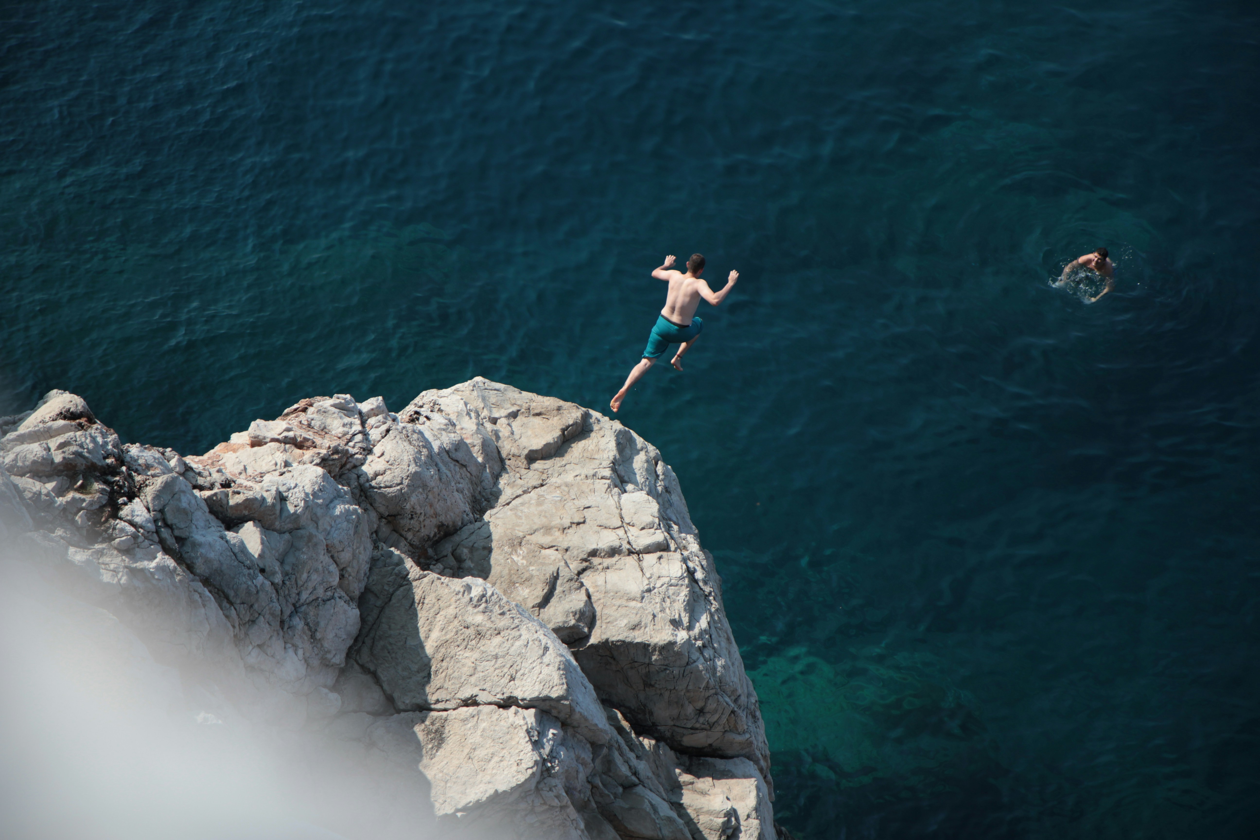 Man Cliff Diving Into Clear Blue Ocean Water. HD mobile wallpaper