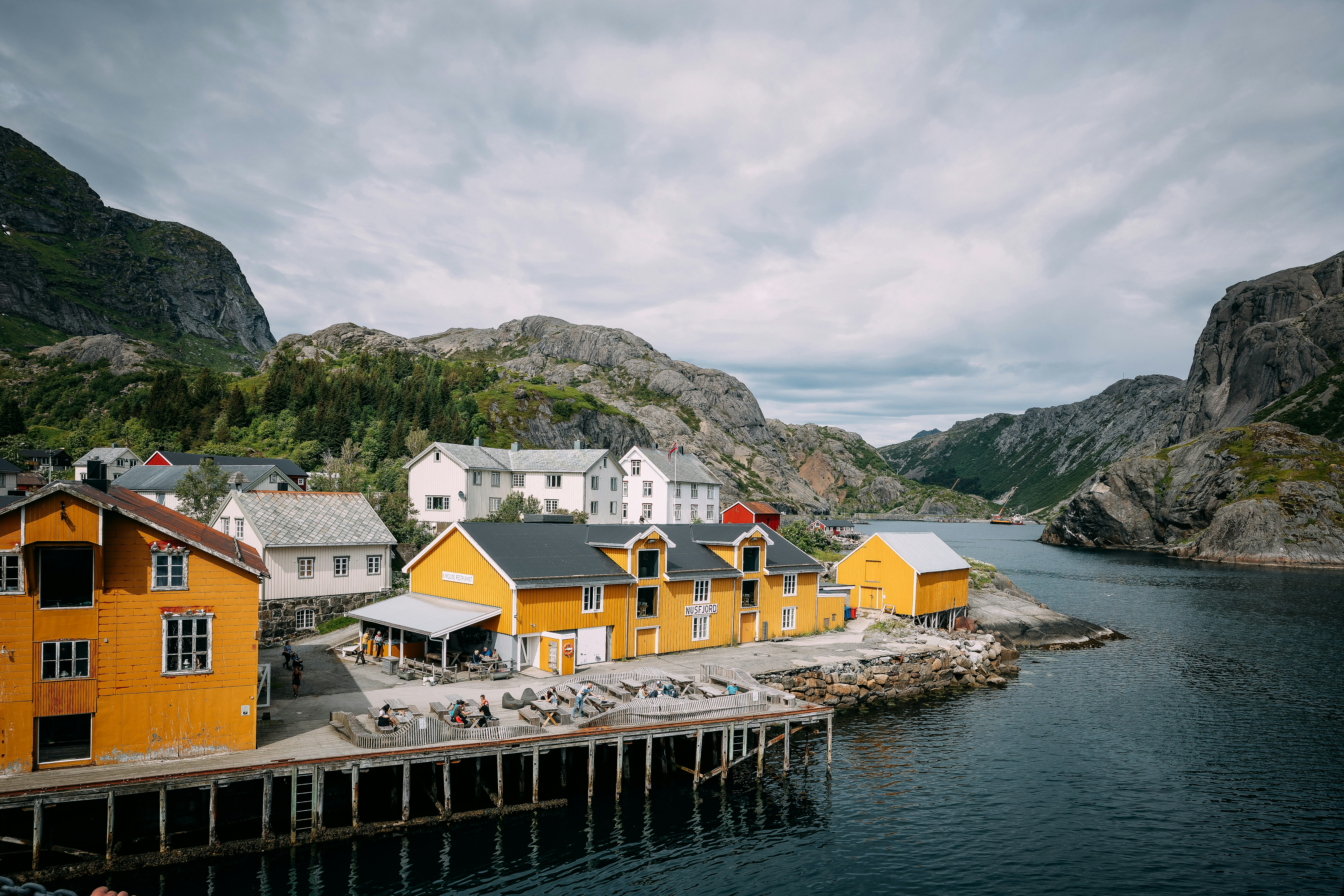 The Colorful Waterfront Of Nusfjord Rests Between Steep Granite Mountains And Calm Arctic Waters. This Scenic View Captures One Of Norway’s Best-preserved Fishing Villages, Blending Traditional Architecture With The Rugged Beauty Of The Lofoten Islands. HD mobile wallpaper