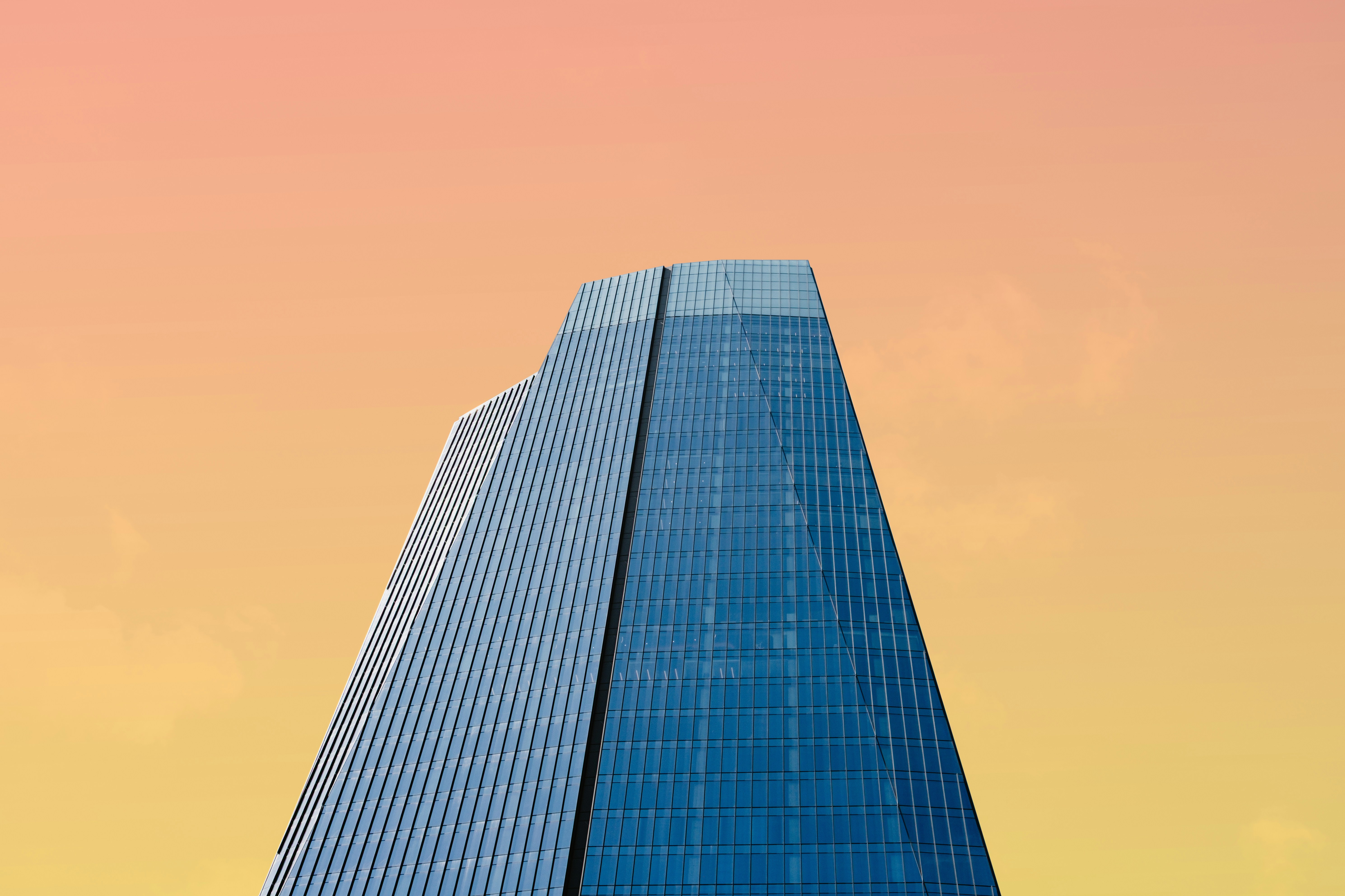 Tall Glass Skyscraper Against Orange And Yellow Gradient Sky HD mobile wallpaper