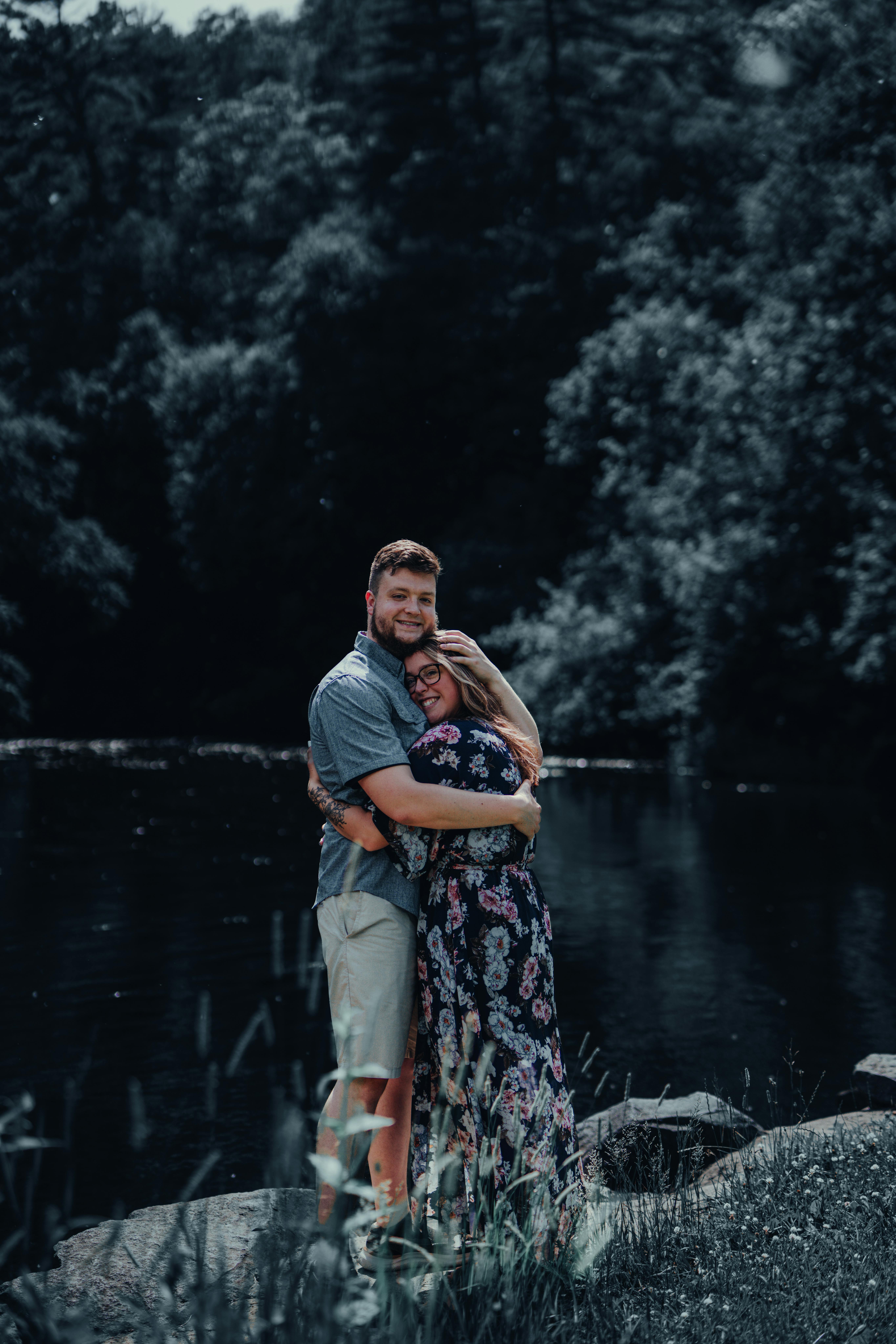 A Loving Couple Embraces By A Peaceful River, Surrounded By Lush Greenery. Perfect For Romantic Themes. HD mobile wallpaper