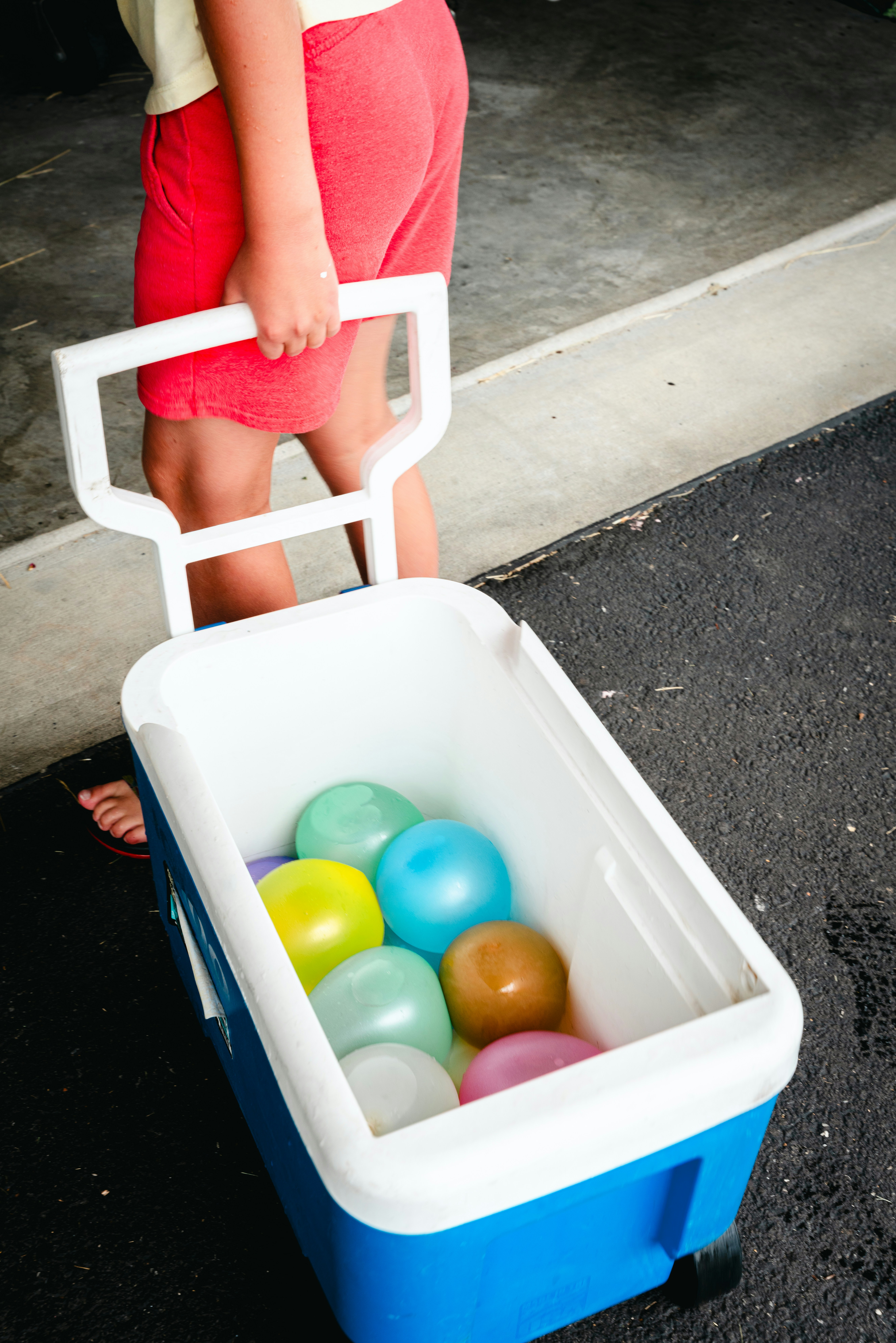 A Child Pulls A Cooler Filled With Colorful Water Balloons. HD mobile wallpaper