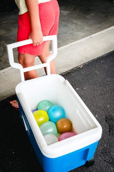 A Child Pulls A Cooler Filled With Colorful Water Balloons. wallpaper preview
