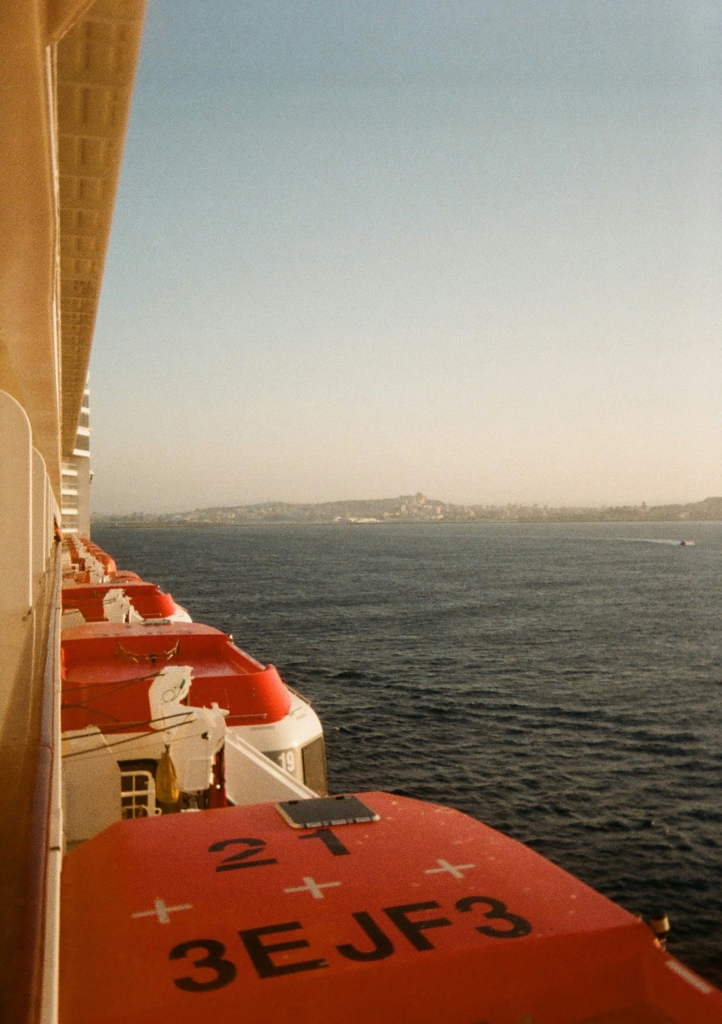Ship's Side With Red Lifeboats, Blue Sea, And Distant Island. HD mobile wallpaper