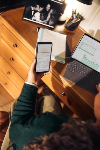 Person Holding Phone Near Laptop And Tablet On Desk wallpaper preview