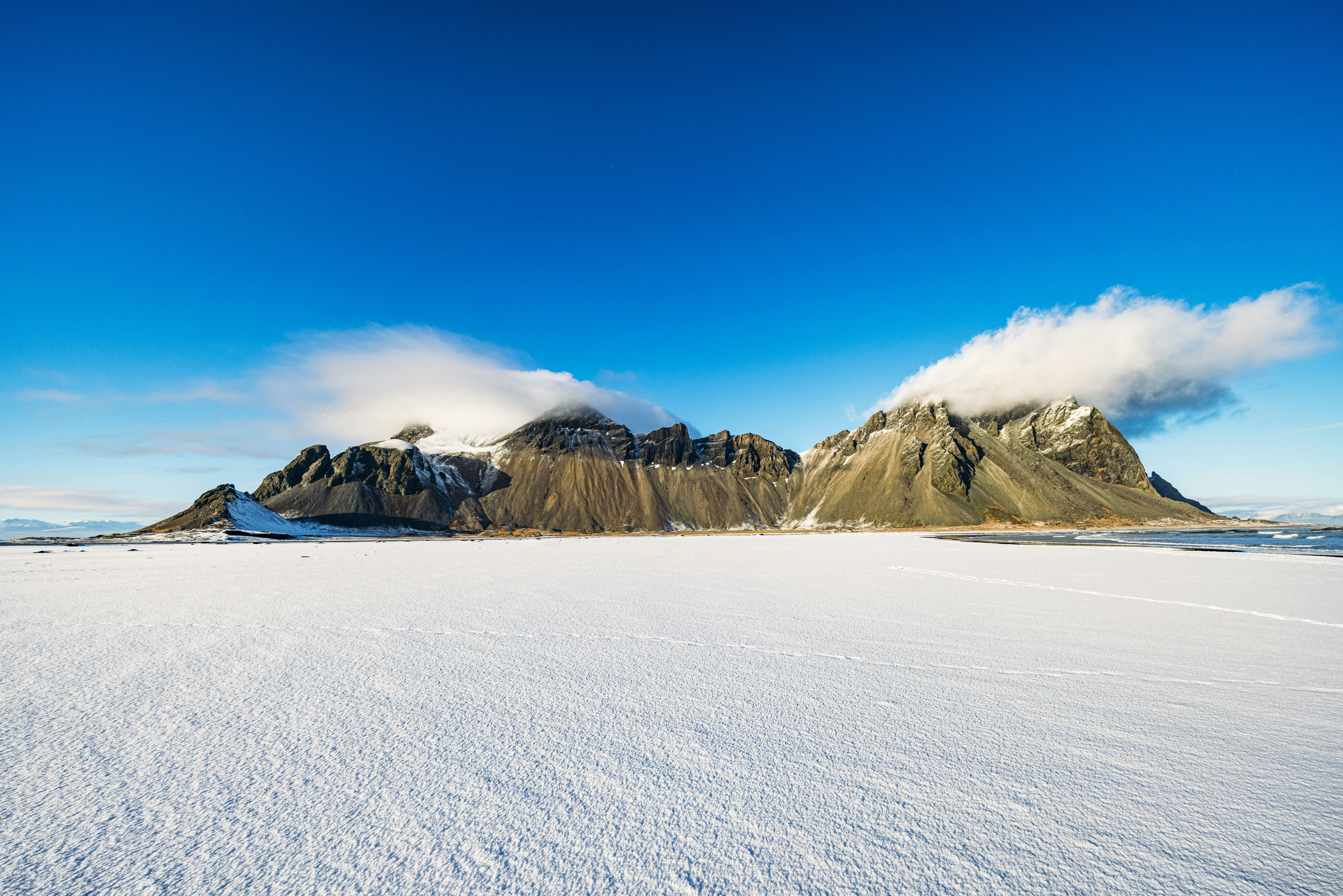 Vast Snowfield Before Rugged Mountains With Clouds Under Blue Sky. HD mobile wallpaper