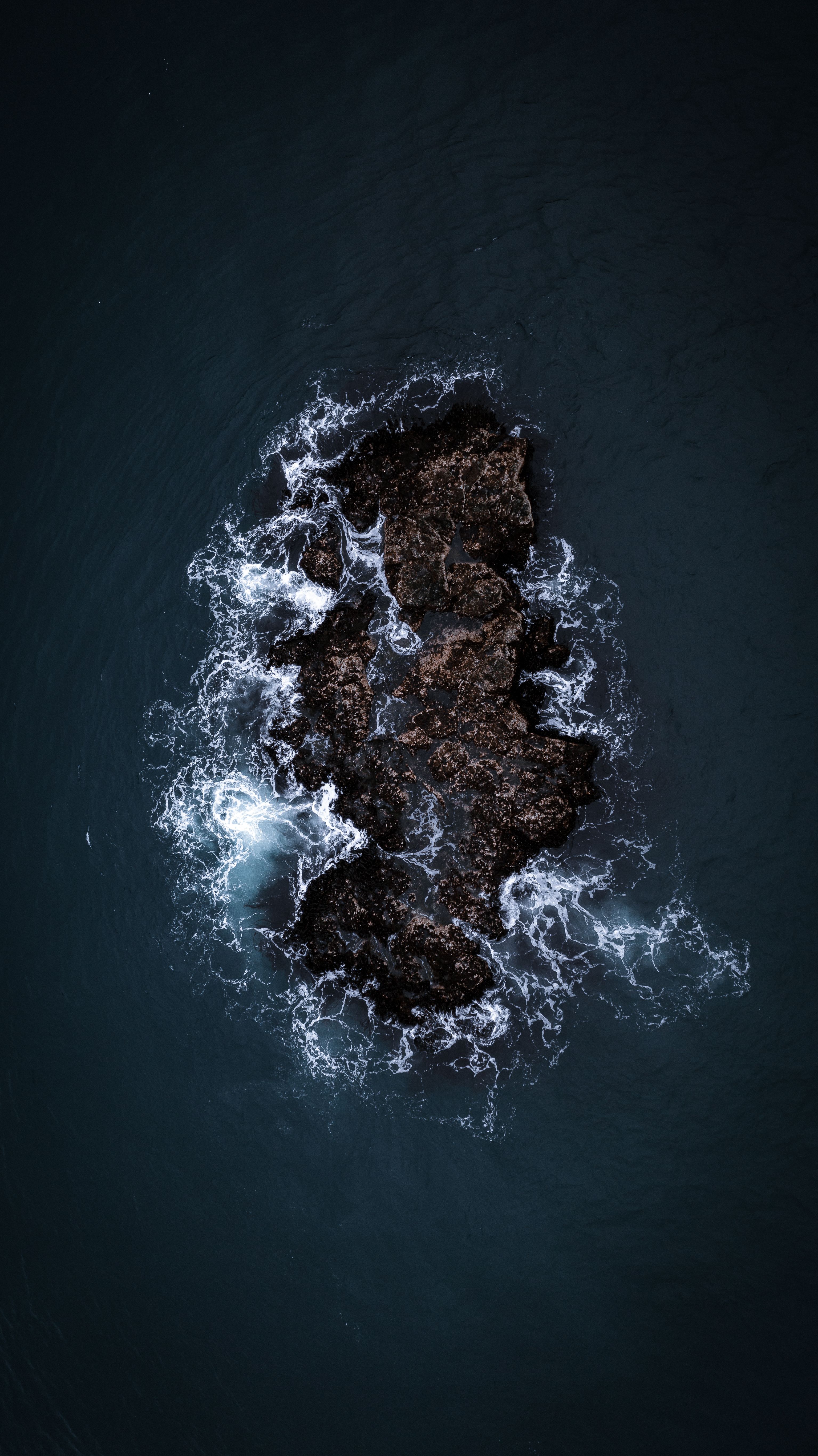 A Dramatic Aerial Shot Captures Waves Crashing Against A Rocky Formation In The Ocean. HD mobile wallpaper