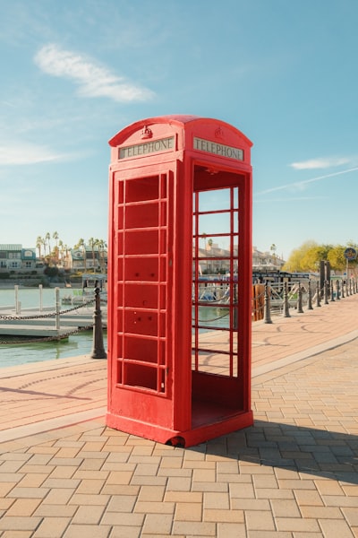 A Red Telephone Booth Stands By A Waterfront. wallpaper preview
