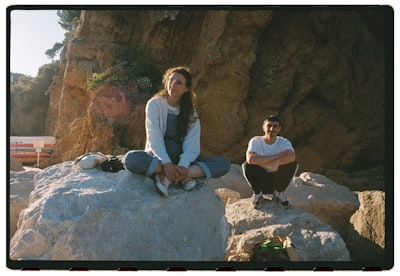 Two People Sitting On Rocks Near The Ocean. wallpaper preview