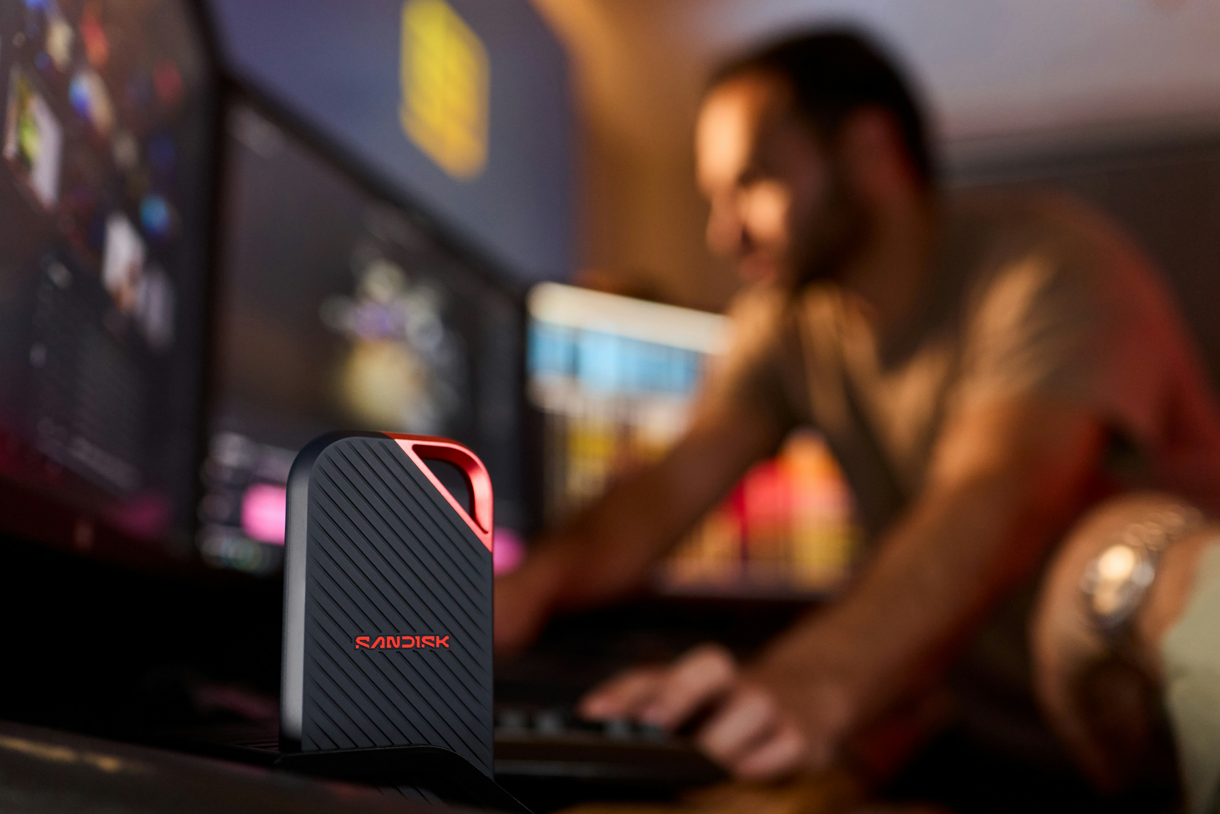 Portable Ssd On Desk With Man Working At Computer. HD mobile wallpaper