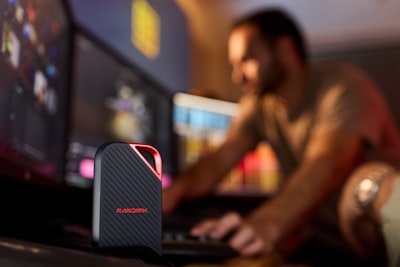 Portable Ssd On Desk With Man Working At Computer. wallpaper preview