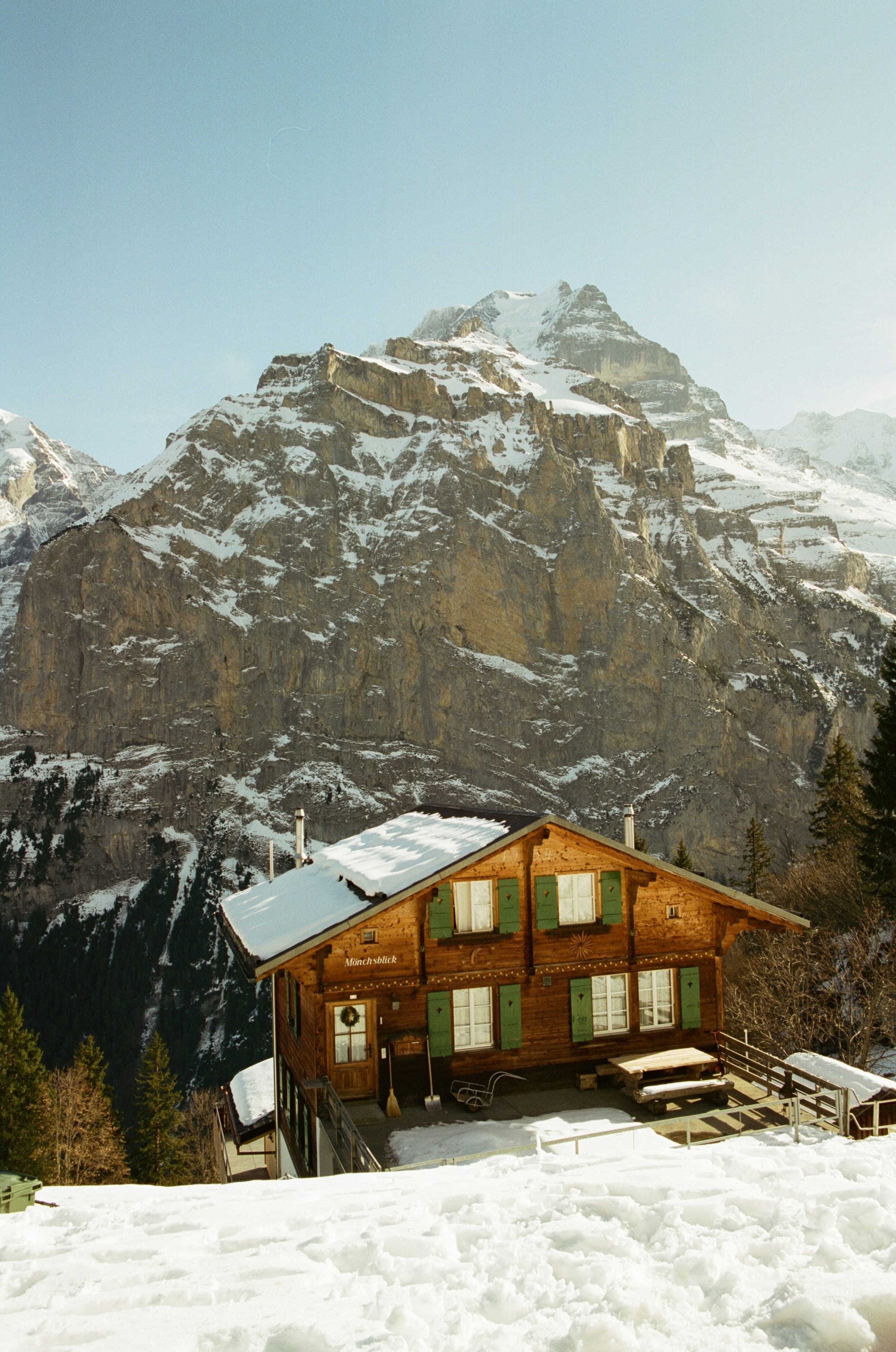 林木山屋與綠色小屋門矗立於雪點點的高山之巔手機桌布高清圖片