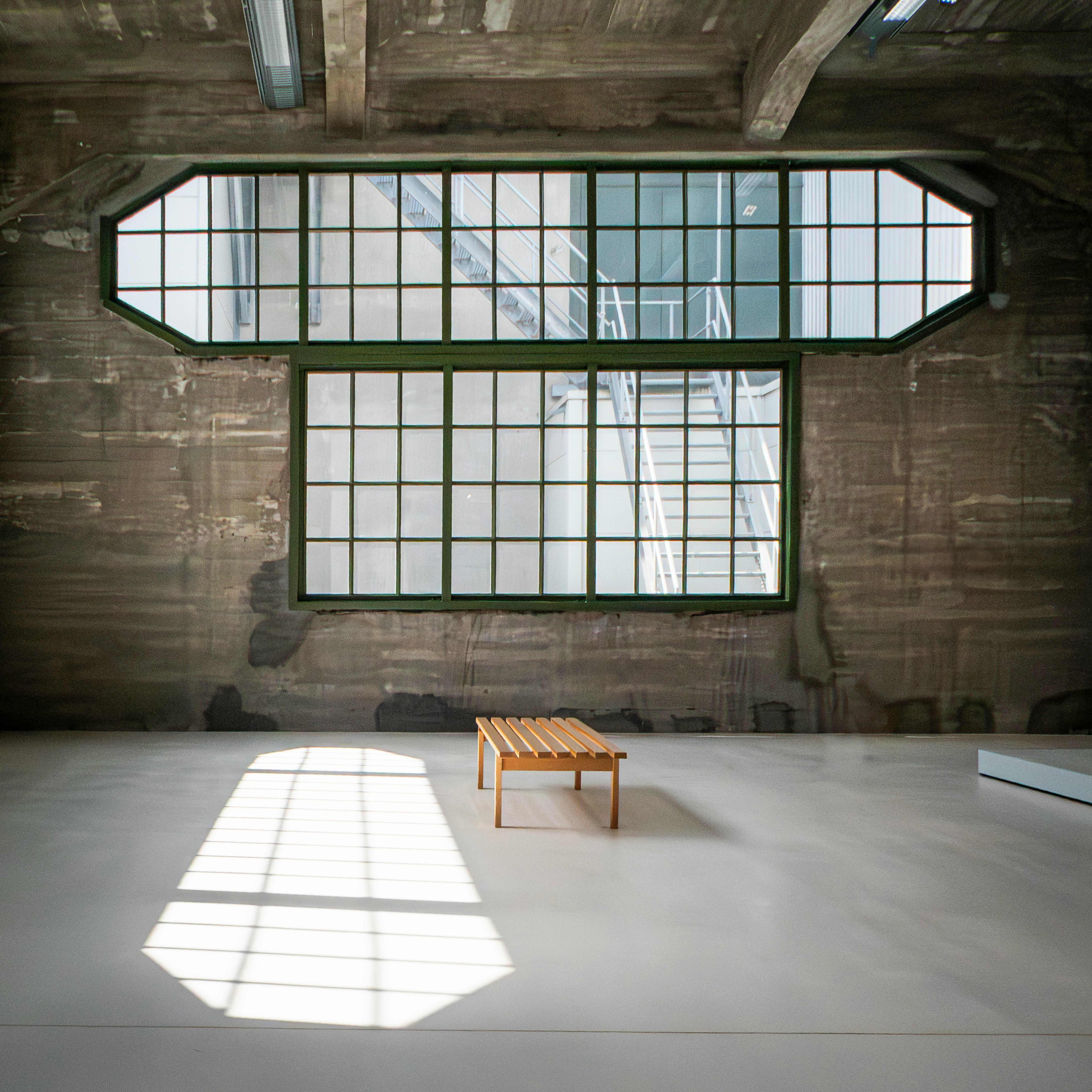 Minimalist Interior Of The Fenix Museum In Rotterdam, Featuring Industrial Architecture, Large Windows, And A Single Wooden Bench Illuminated By Soft Natural Light. HD mobile wallpaper