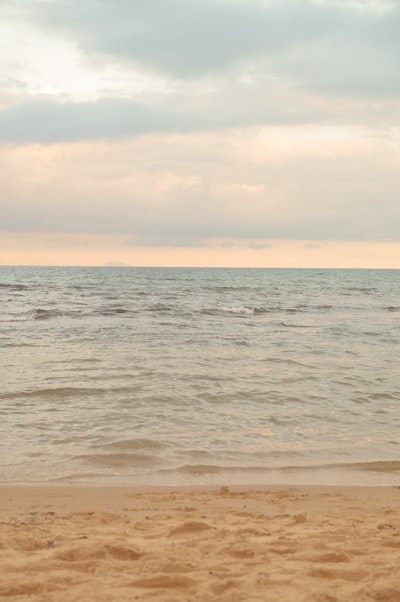 Sandy Beach, Calm Ocean, And Soft Cloudy Sky. wallpaper preview