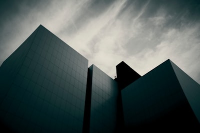Dark, Angular Modern Buildings Against A Dramatic Cloudy Sky. wallpaper preview