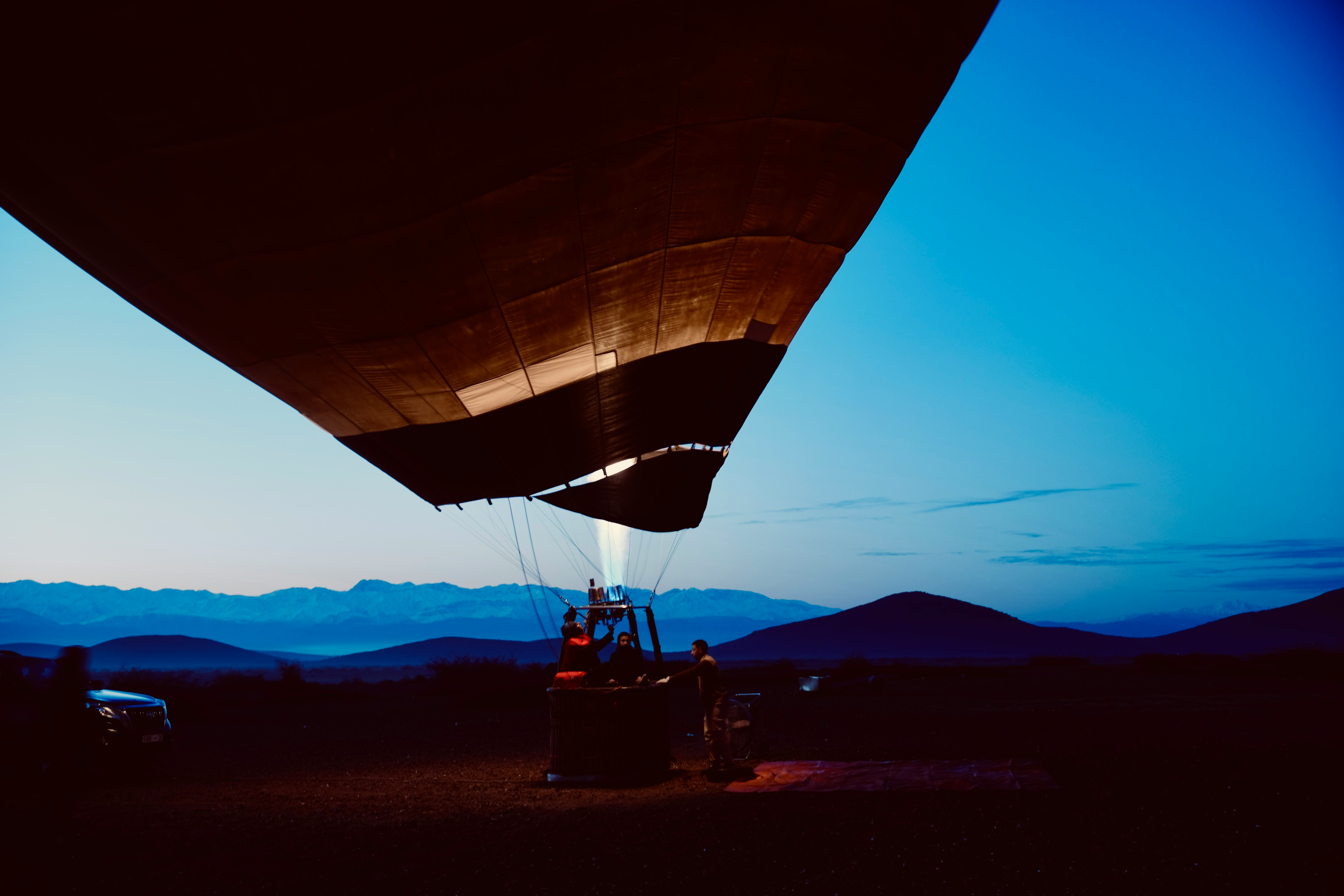 Hot Air Balloon Inflation At Twilight Over Mountains. HD mobile wallpaper