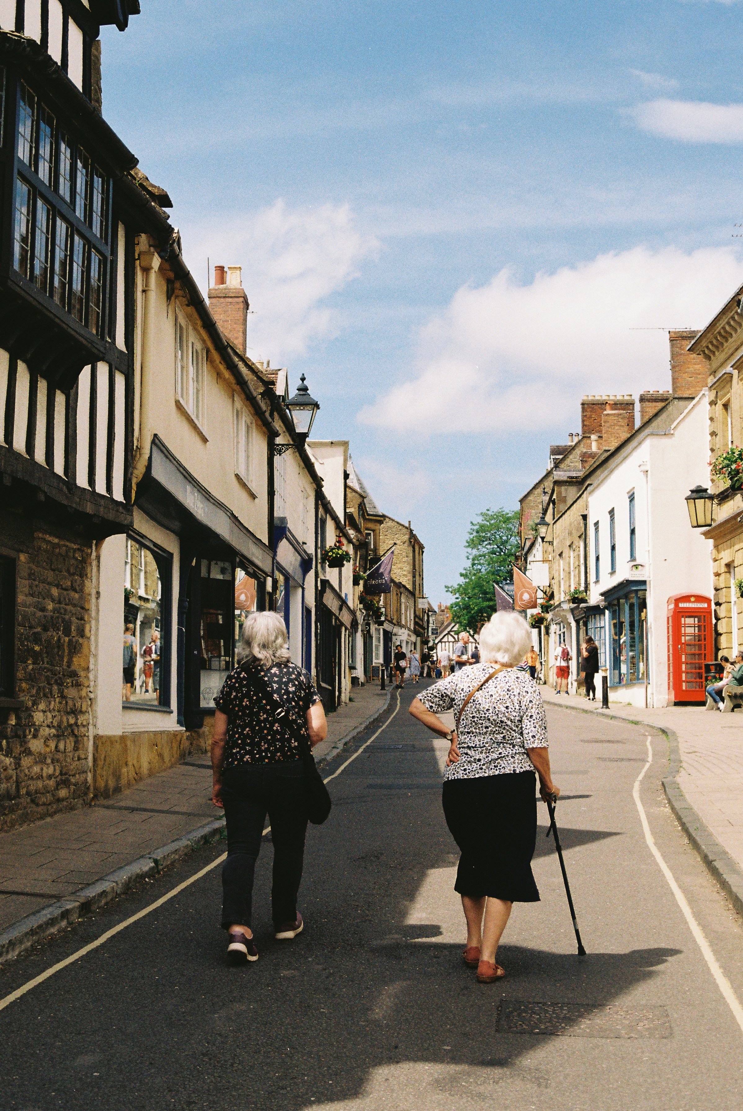 Two Elderly Women Walk Down A Charming Old Town Street. HD mobile wallpaper