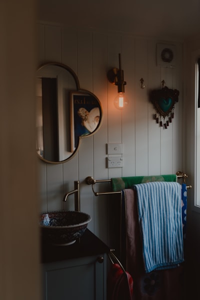 Bathroom With Warm Light, Round Mirror, Decorative Sink, And Towels. wallpaper preview