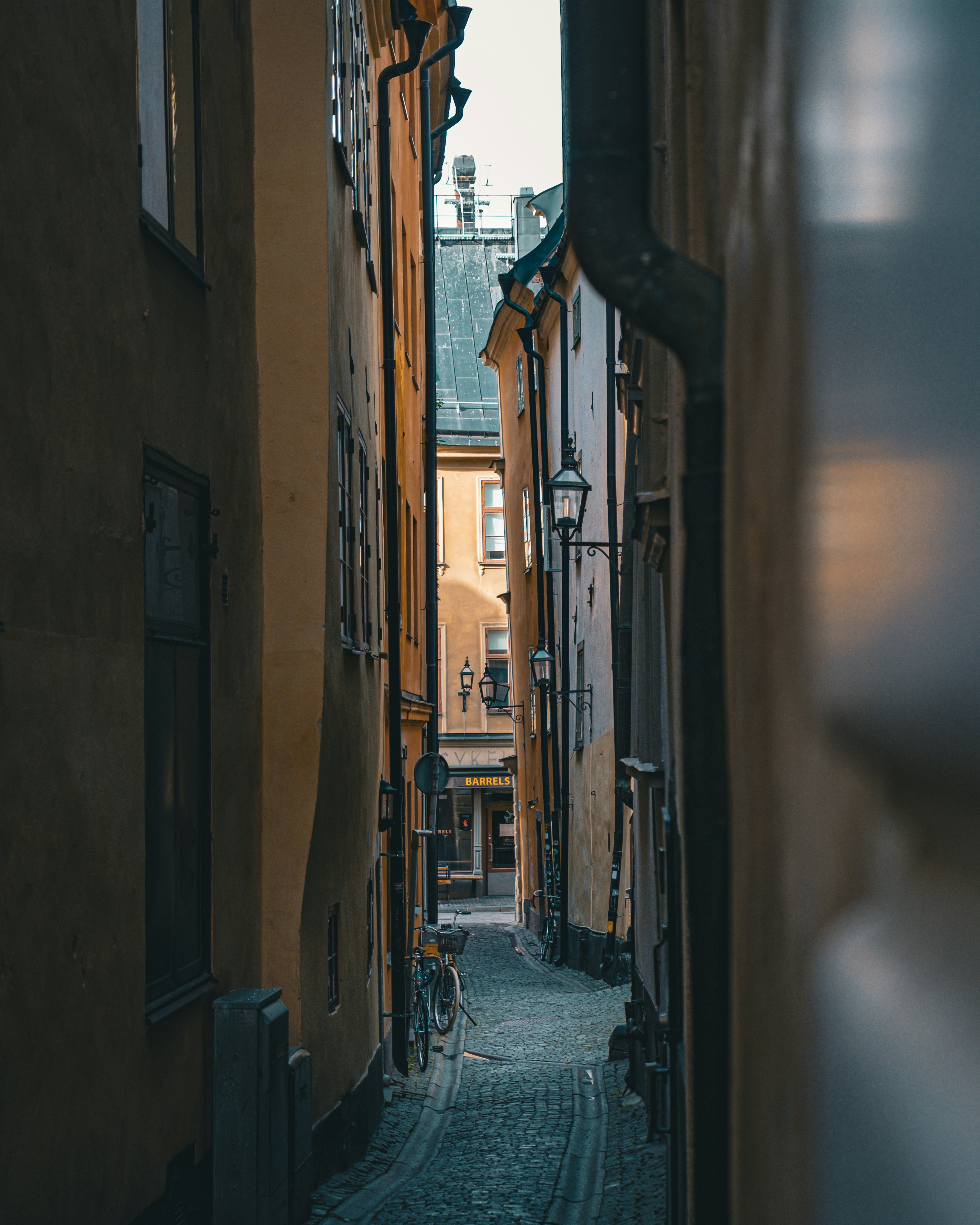 Cobblestone Street In Gamla Stan, Stockholm's Medieval Old Town, Lined With Colorful Historic Facades In Warm Ochre And Terracotta Tones With A Bicycle In The Distance HD mobile wallpaper