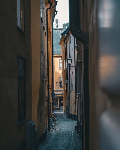 Cobblestone Street In Gamla Stan, Stockholm's Medieval Old Town, Lined With Colorful Historic Facades In Warm Ochre And Terracotta Tones With A Bicycle In The Distance wallpaper preview