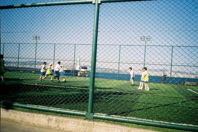 Children Play Soccer On A Turf Field Near The Ocean. wallpaper preview