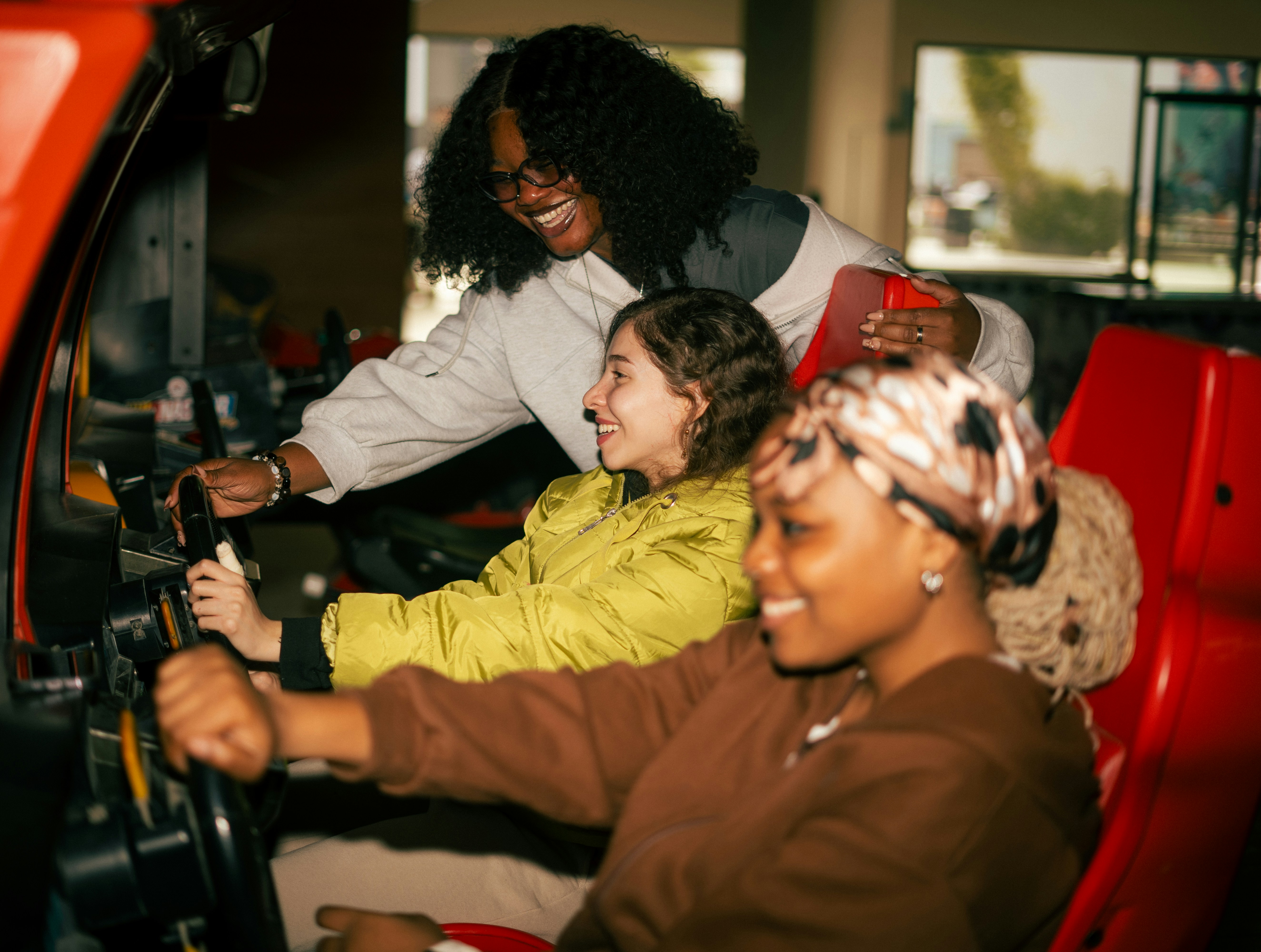 Three Friends Playing A Racing Arcade Game Together HD mobile wallpaper