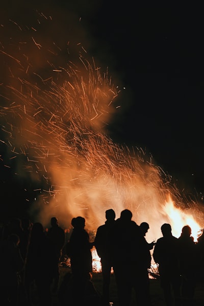 Silhouettes Of People Gathered Around A Large Bonfire At Night. wallpaper preview