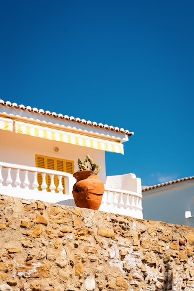 Mediterranean Building With Yellow Awning And Potted Plant. wallpaper preview