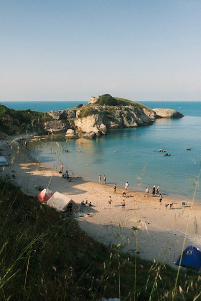 People Relaxing On A Sunny Beach With A Rocky Island. wallpaper preview