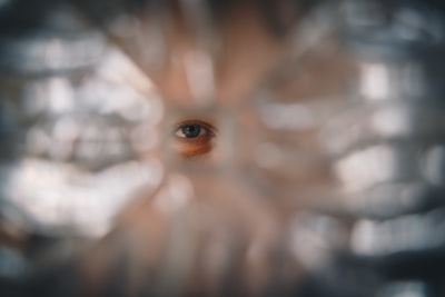 A Blue Eyed Woman Looking Through A Hole In The Glass wallpaper preview