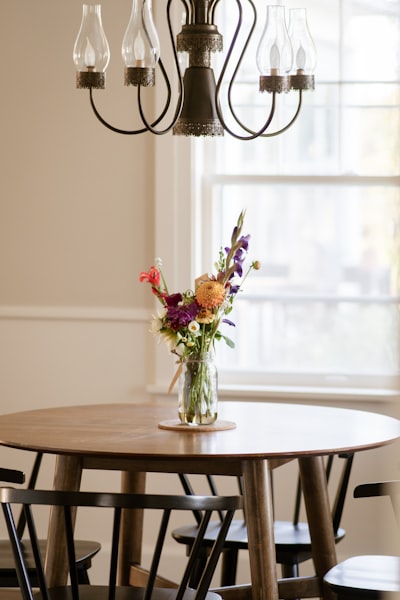 A Vase Of Colorful Flowers Sits On A Wooden Table. wallpaper preview
