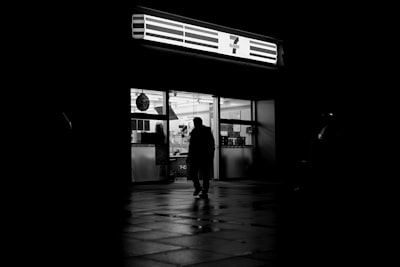 Man Walks Into A Brightly Lit Store At Night wallpaper preview