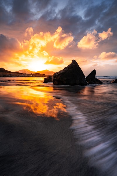 夕陽落山於磯岩海灘, 浪潮激蕩的壯麗夜景桌布預覽