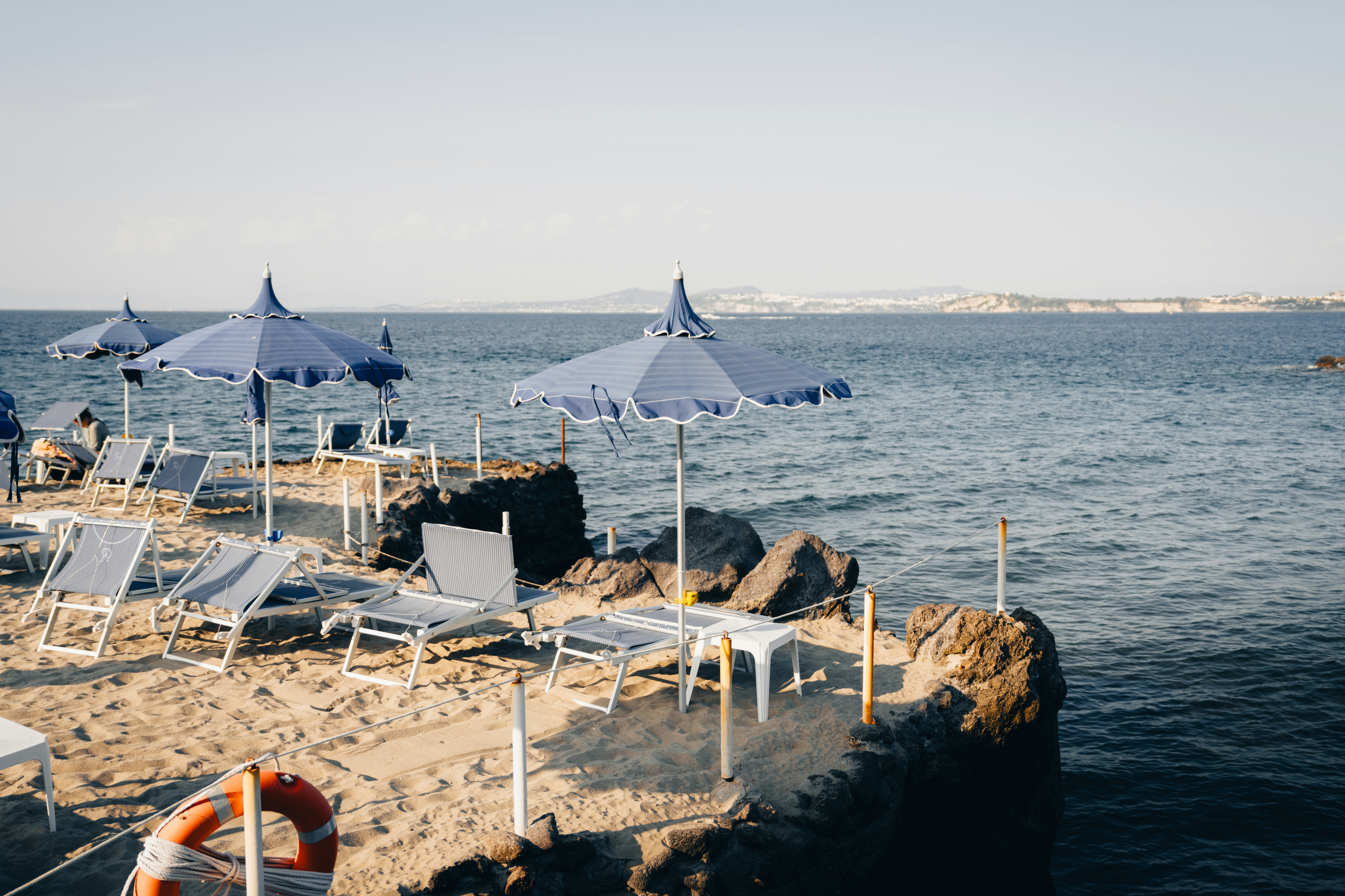 Sandy Beach With Blue Umbrellas, Lounge Chairs, And Ocean View. HD mobile wallpaper