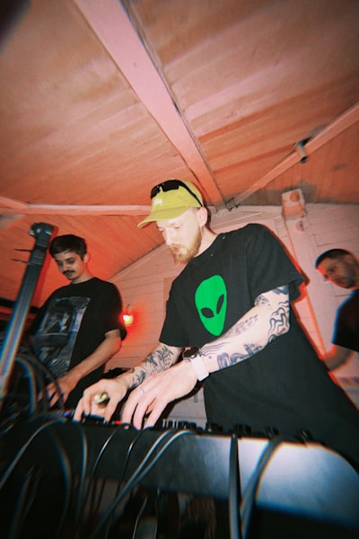 Man With Alien Shirt Operates Dj Equipment At An Event. wallpaper preview