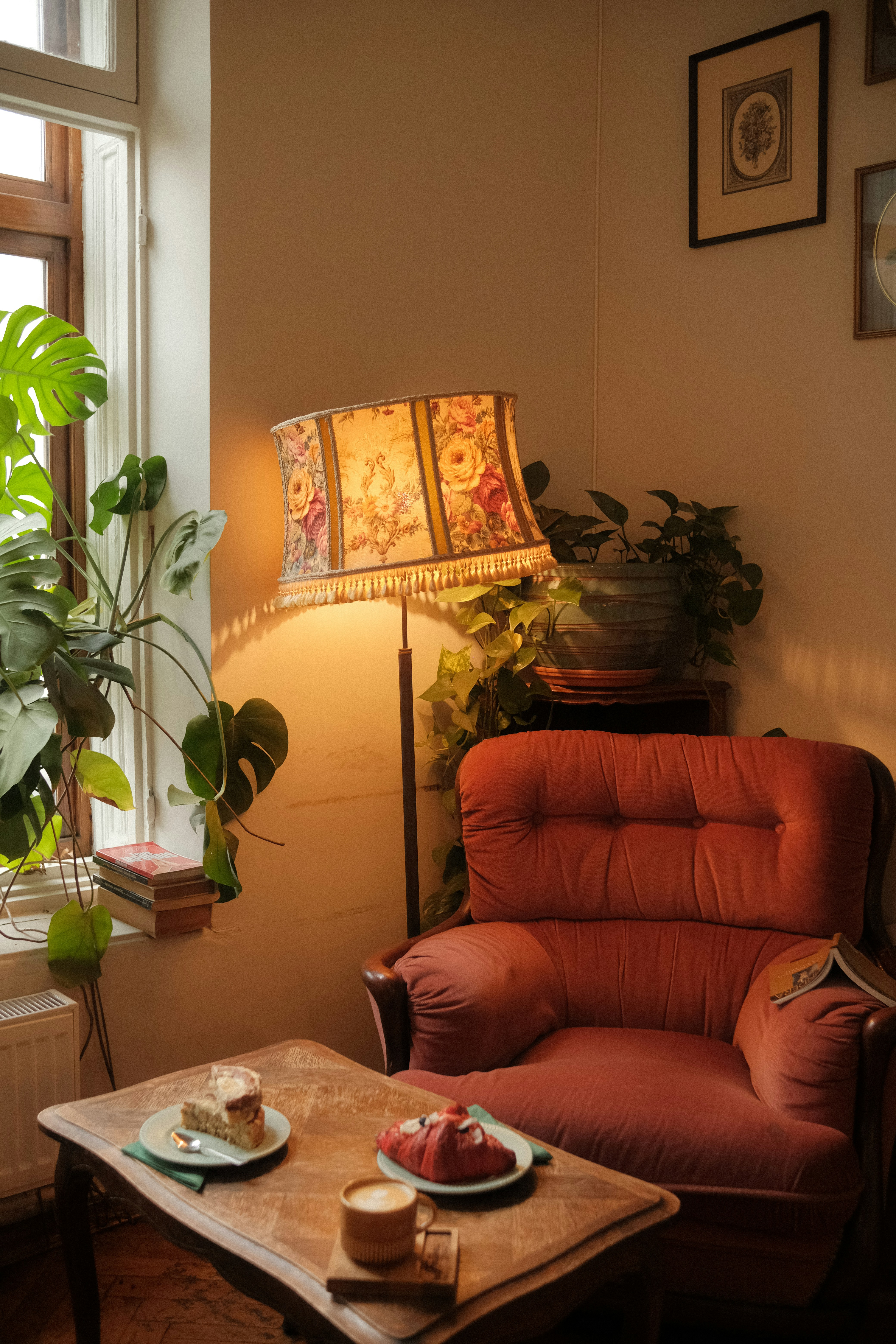 A Warm Café Corner With A Vintage Armchair, Floral Lampshade, Indoor Plants, Pastries, And Coffee On A Wooden Table, Creating A Nostalgic And Intimate Atmosphere. HD mobile wallpaper