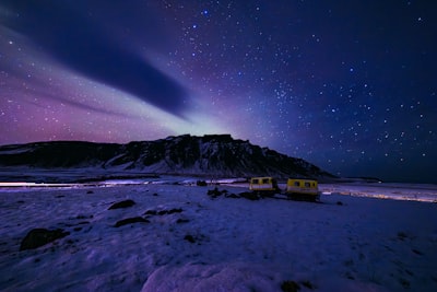 Northern Lights Illuminate A Snowy Mountain Landscape With Small Buildings. wallpaper preview