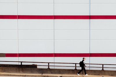Man Walks Past A Building With Red Stripes. wallpaper preview