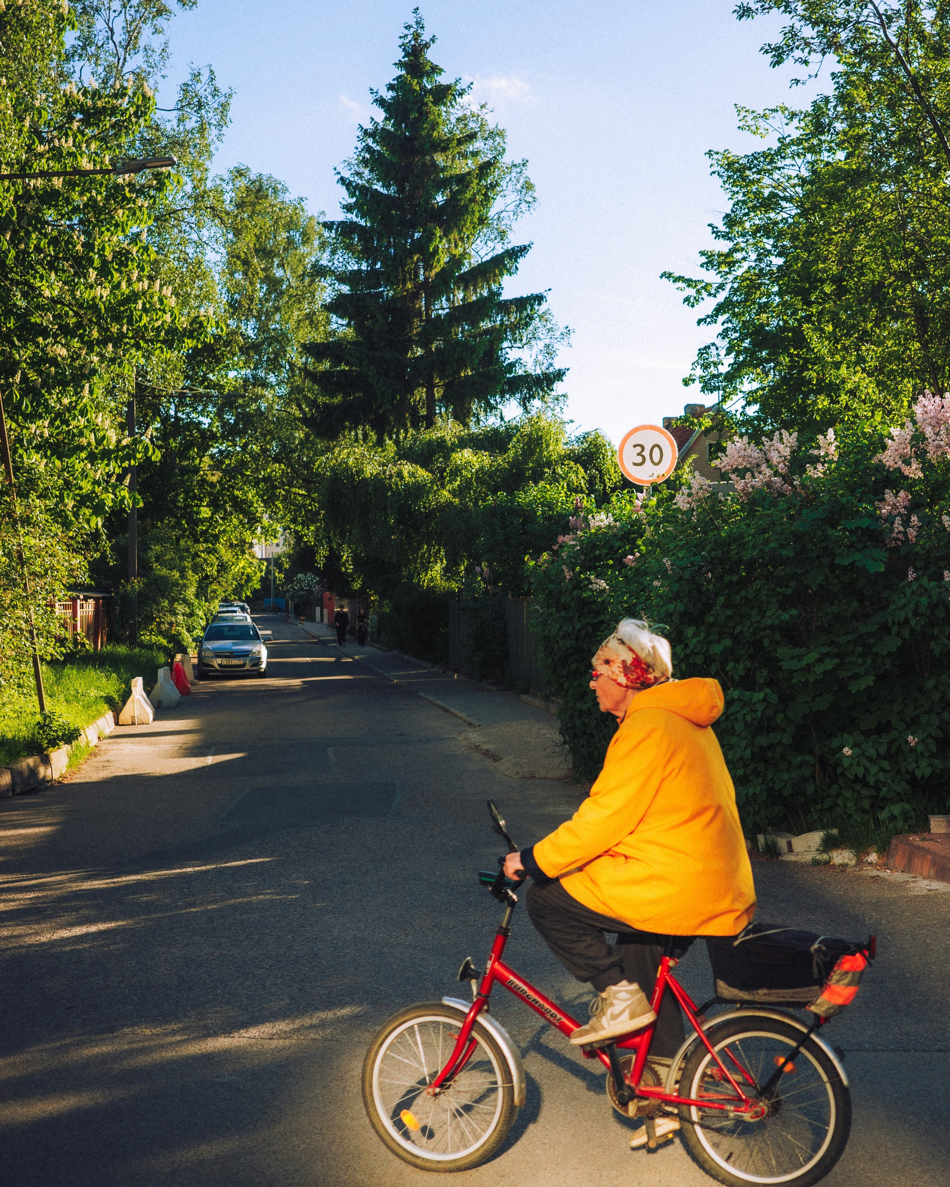 Older Person In Yellow Jacket Rides Red Bicycle On Street. HD mobile wallpaper