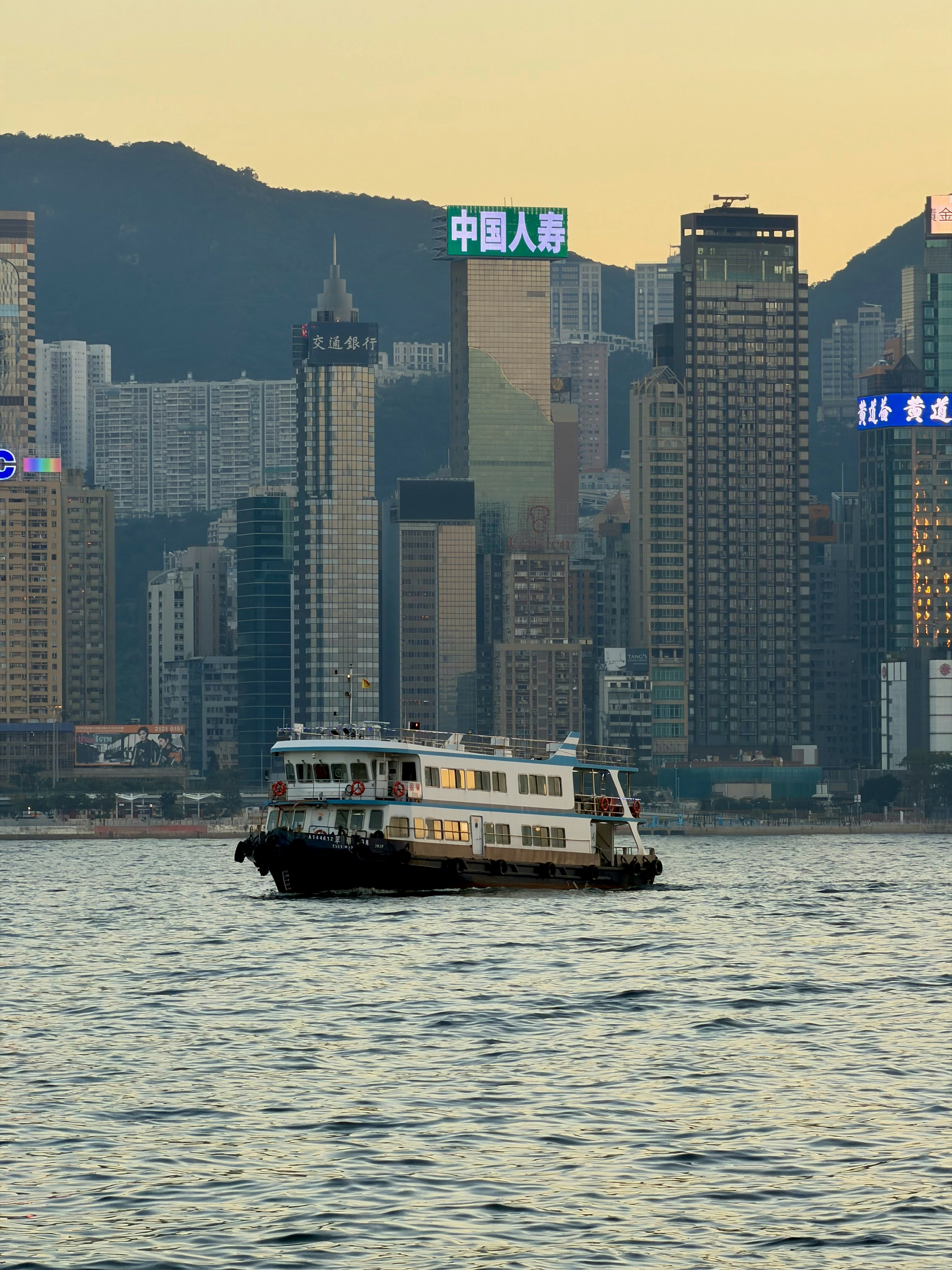 渡輪緩慢駛過海灣，城市天際線在背景中靜靜凝望手機桌布高清圖片