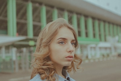 Young Woman With Wavy Hair Looking Away, Green Building Background. wallpaper preview