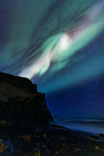Aurora Borealis Illuminates Dark Night Sky Over Ocean And Cliffs. wallpaper preview