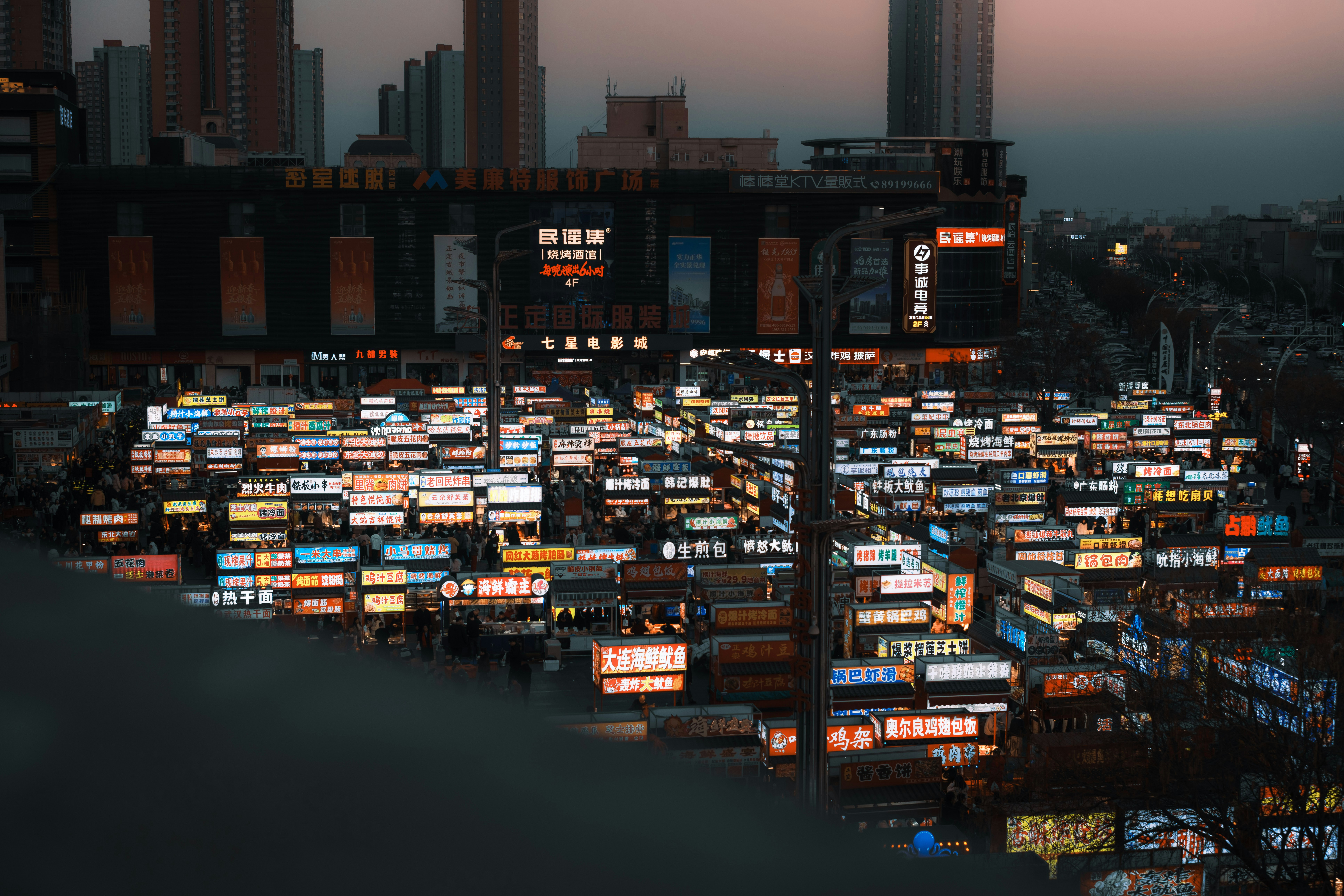 A Dense Cityscape Illuminated By Numerous Glowing Signs At Dusk. HD mobile wallpaper