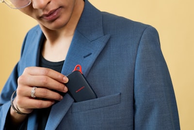 Hand Inserting A Black Electronic Device Into A Blazer Pocket. wallpaper preview