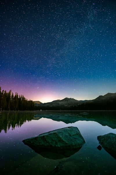 Starry Night Sky Over A Serene Lake With Mountain Reflections. wallpaper preview