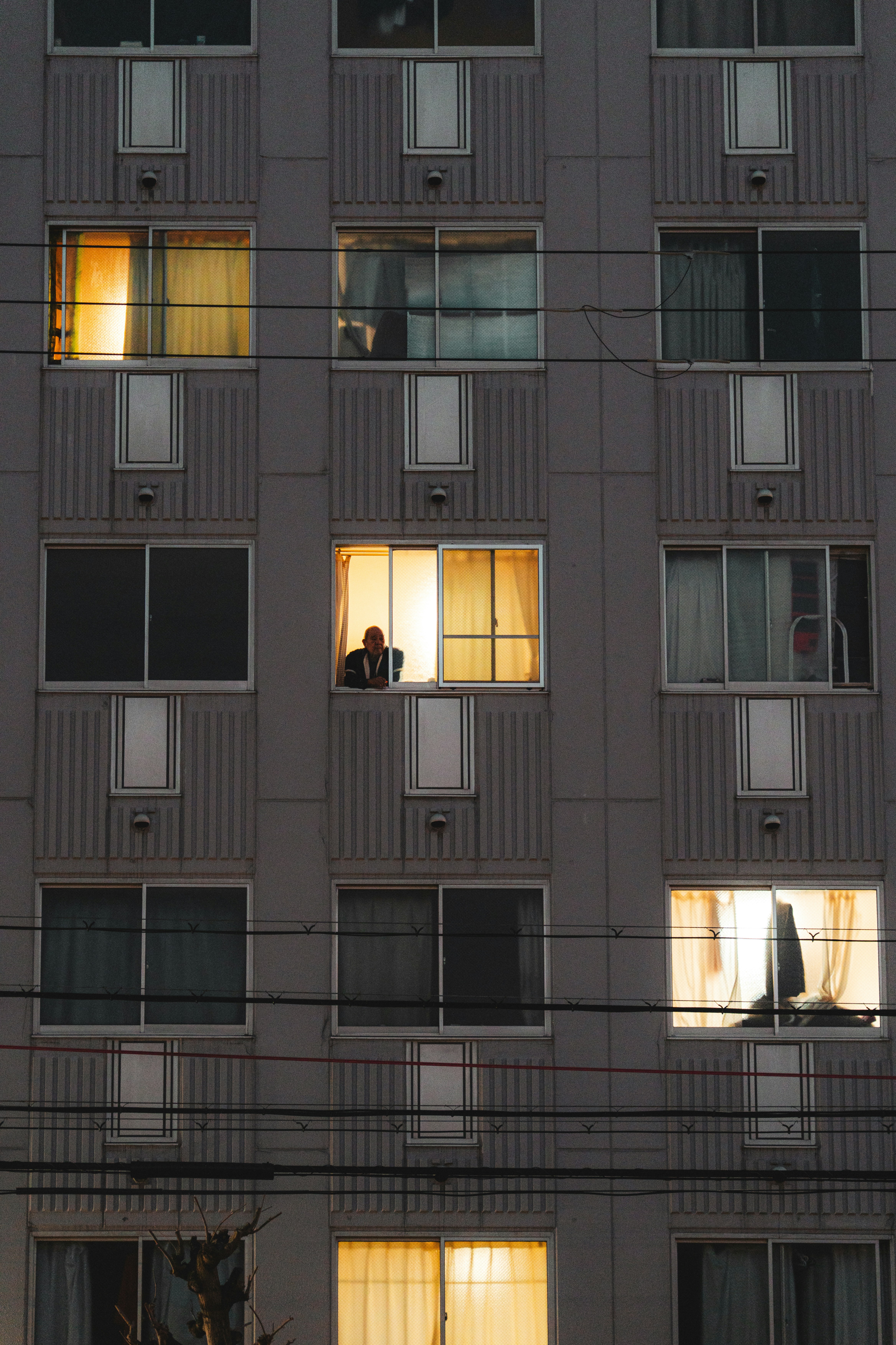 A Person Looks Out From A Brightly Lit Apartment Window. HD mobile wallpaper