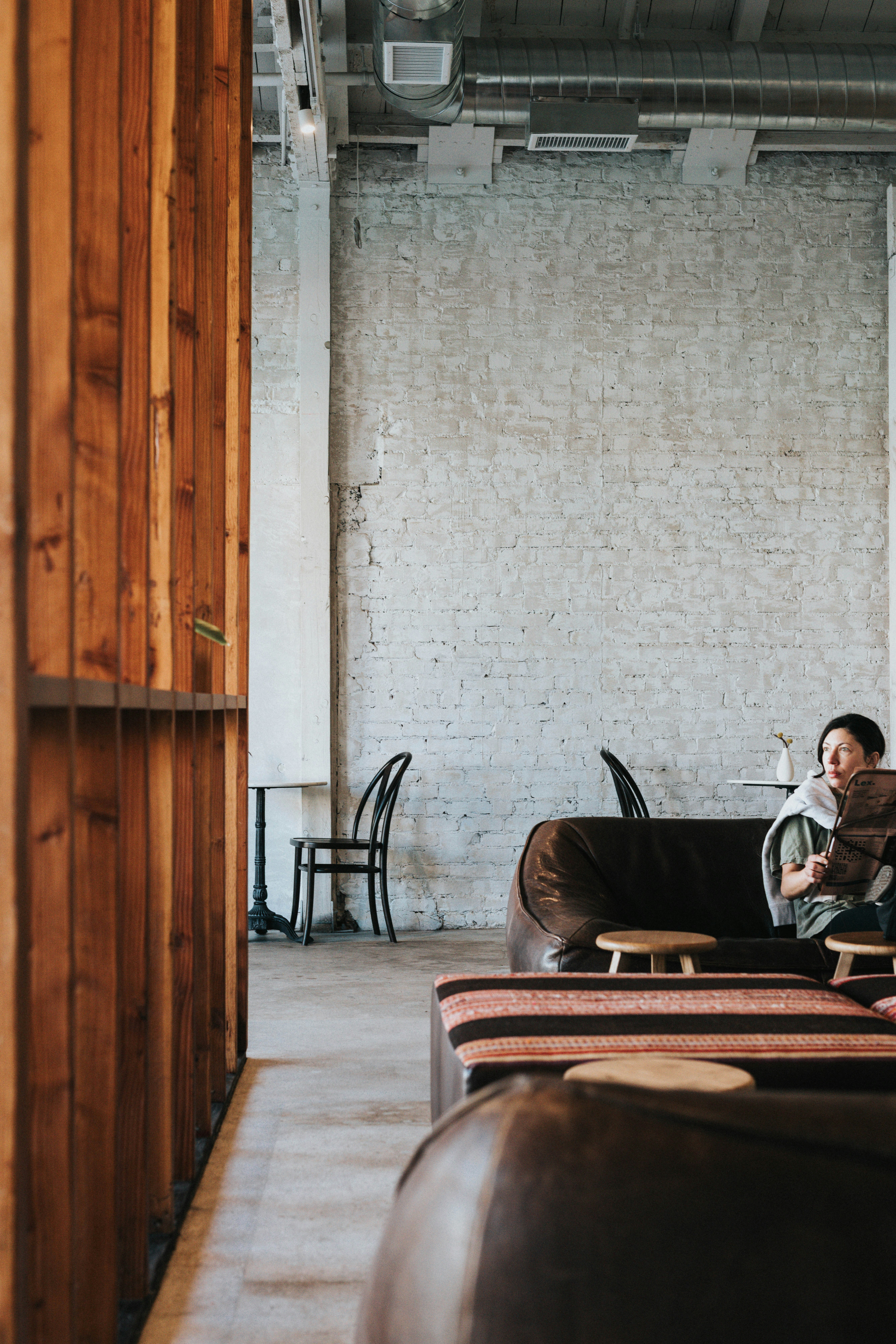 Person Relaxing On A Leather Couch In A Modern Cafe. HD mobile wallpaper